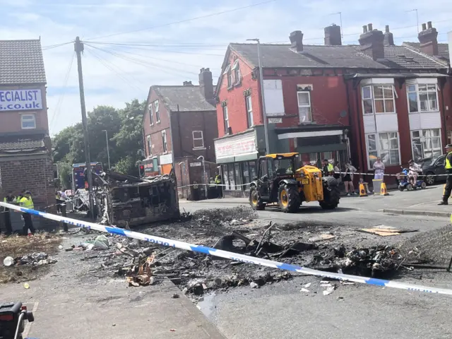 Remains of a bus that was set on fire in Harehills, Leeds, with police tape around it