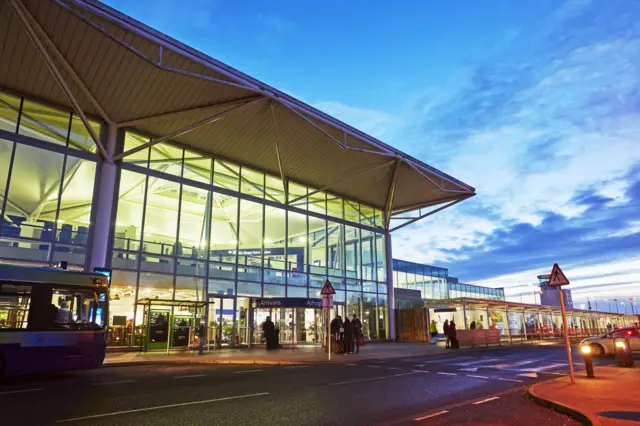 Entrance to Bristol Airport at dusk, with street lights outside.