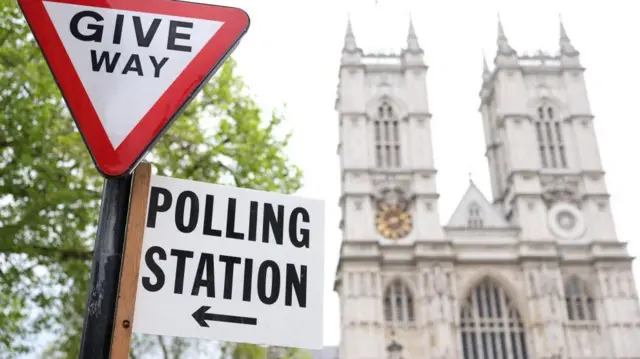 polling station direction sign is attached to a street sign near to Westminster Abbey, ahead of local elections, in London, Britain, May 1, 202