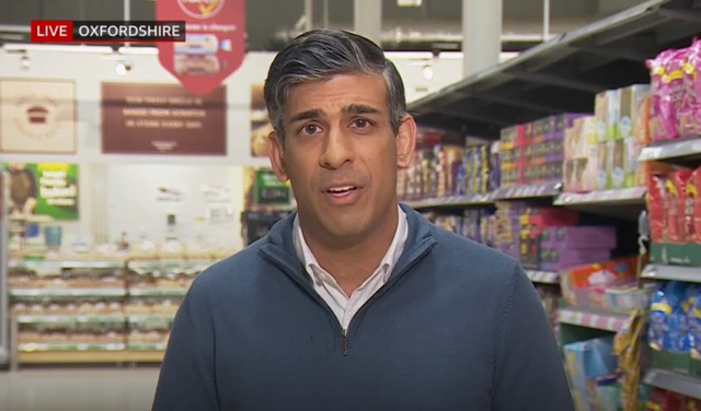 Prime Minister Rishi Sunak during a live interview on BBC Breakfast, standing in the aisles of a supermarket with products behind him