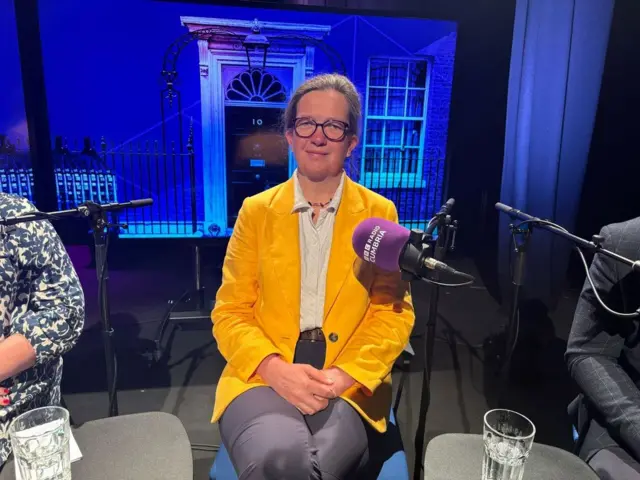 Liberal Democrat candidate Julia Aglionby wears a yellow jacket and sits in the ˿ Cumbria election debate studio