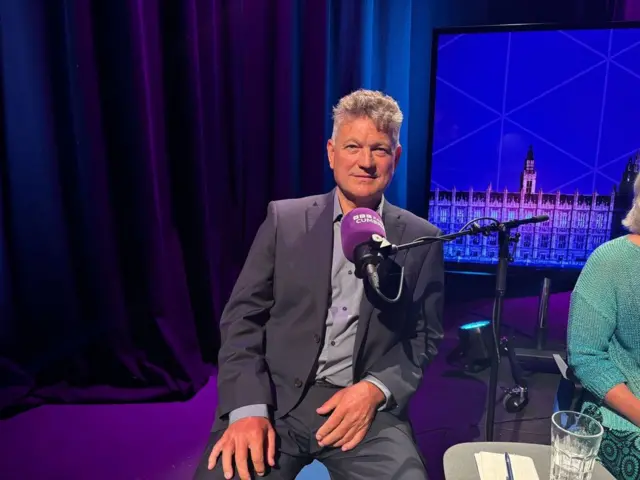 Conservative Mike Starkie sits in the ˿ Cumbria election debate studio wearing a grey suit and grey shirt