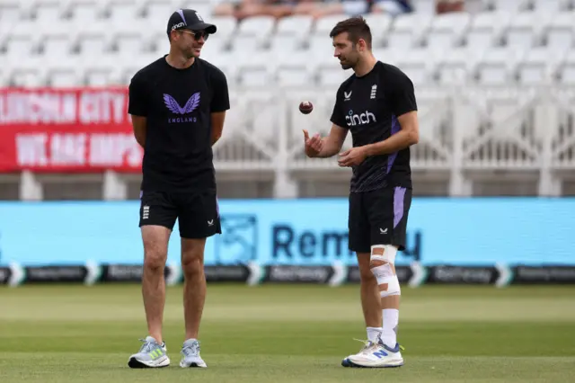 Mark Wood's left knee and leg is heavily strapped as he speaks to James Anderson in the warm-up