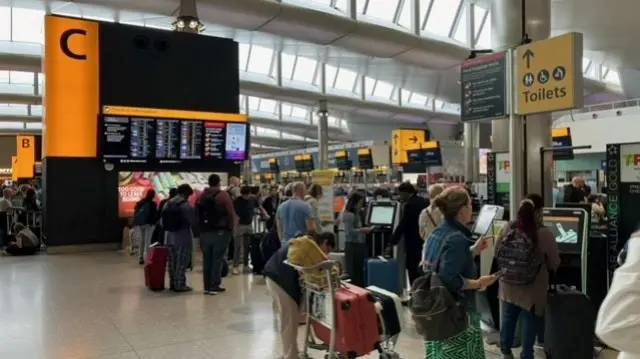 People surround digital check in machines at airport