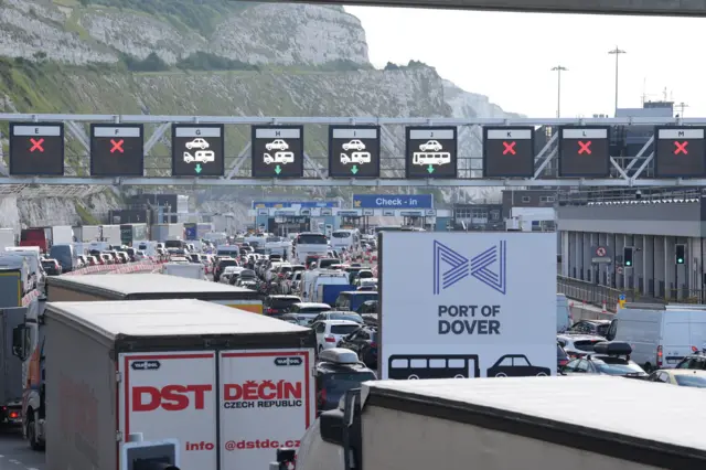 Queues of cars and lorries below digital check-in signs