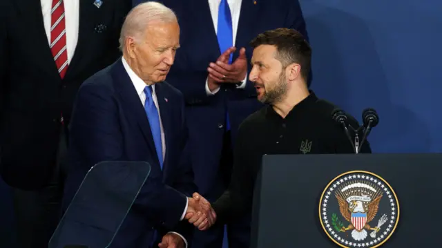 Biden shakes Zelensky's hand in front of a podium