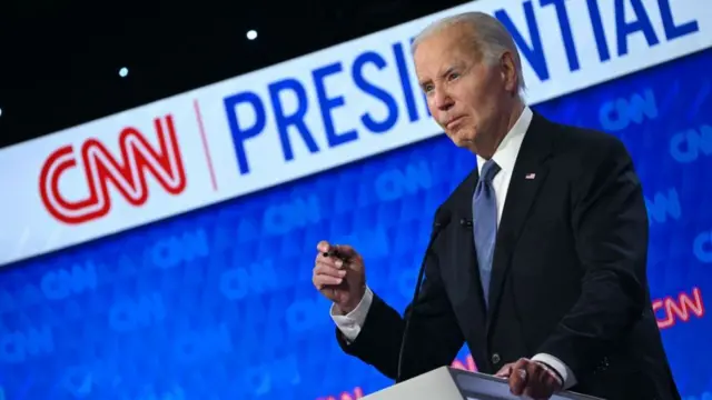 Biden at podium with hand raised