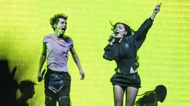 Two people on stage with a bright green background