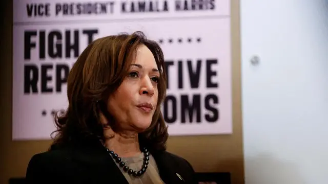 Harris stands in front of a banner about reproductive freedoms