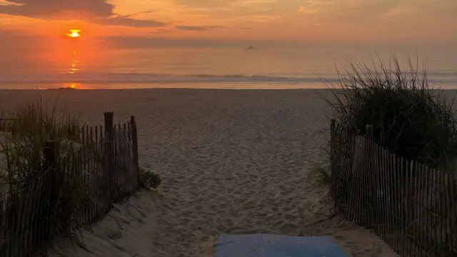 A picture of the sun rising over the beach