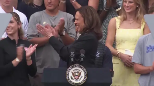 Harris applauding the athlete coming onto the stage