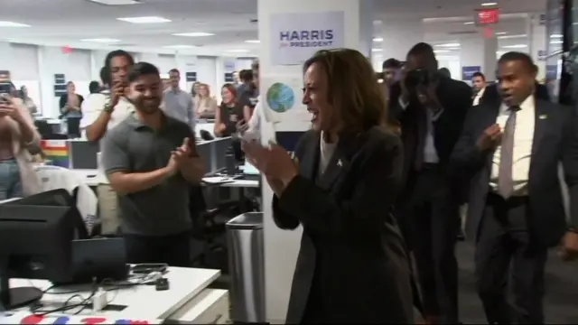 Harris smiles and claps as she walks through an office