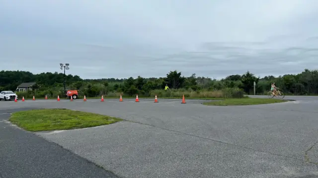 Witch's hats line a road as cyclists pass by