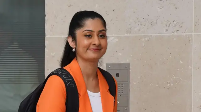 Zarah Sultana walking, she is wearing a rucksack and a bright orange jacket