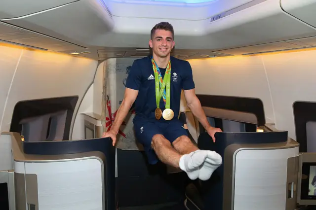 Max Whitlock balances on two seats while wearing his Olympic medals