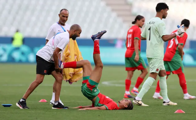 Targhalline Oussama has his leg stretched by a coach