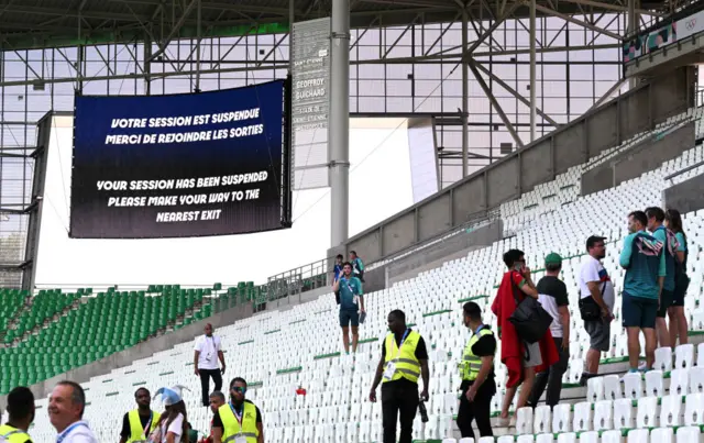 A screen in Geoffroy-Guichard Stadium shows a message saying "your session has been suspended please make your way to the nearest exit"