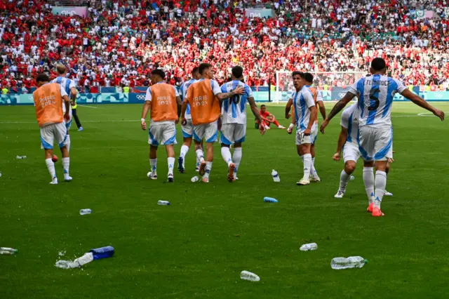 Bottles on a football pitch next to Argentina players