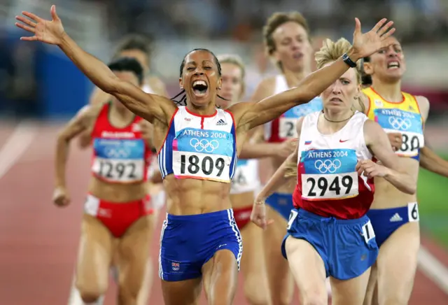 Dame Kelly Holmes holds out her arms as she celebrates winning the 1500m