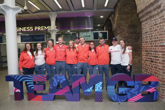 The GB archery team stand behind a Team GB sign