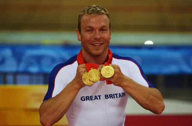 Chris Hoy holds up three gold medals