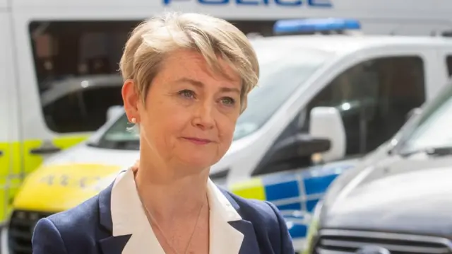 Yvette Cooper speaking in front of police vehicles