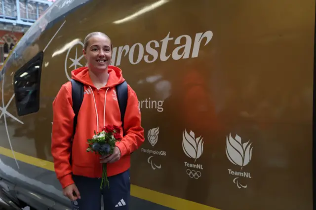 Charley Davison holds flowers and stands in front of the EuroStar