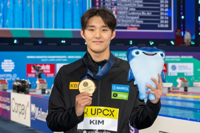 Kim Woo-min holds up a meddle and a cuddly toy