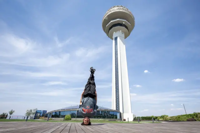 Furkan Coskun stands on his head in front of the Atakule Tower