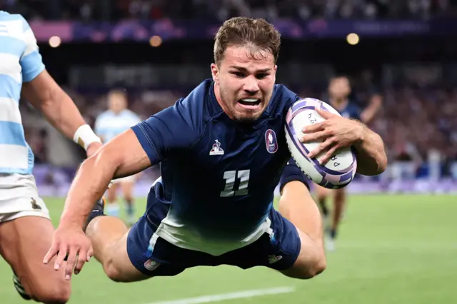 Antoine Dupont dives with a rugby ball in his hand