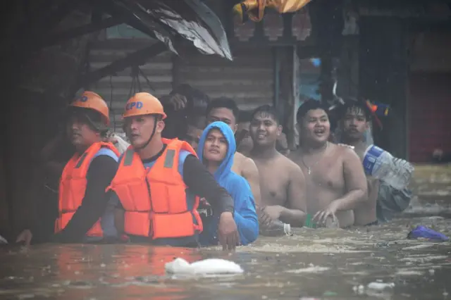 Rescuers (front L) guide residents with their belongings as they evacuate from their flooded homes in Tumana village, Marikina City, east of Manila on July 24, 2024