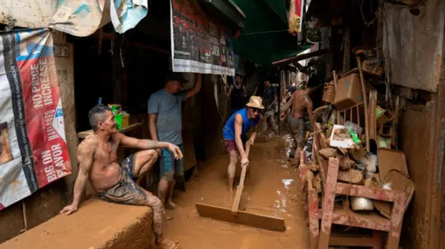 A man sweeps muddy water out of an narrow alley