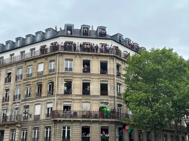 Fans stand on balconies and watch the Olympics opening ceremony