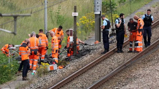 Rail workers wearing high vis work among cables at the side of a railway track