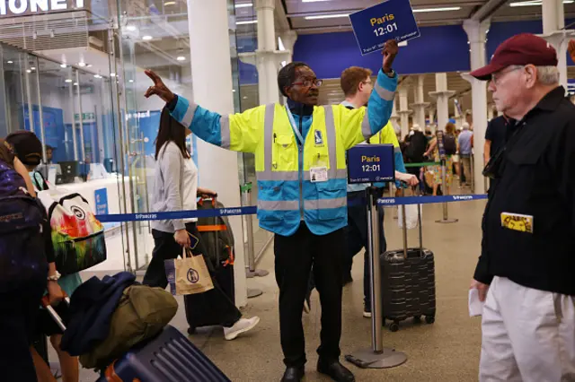 A staff member directs travelers as the Eurostar service experienced delays at St Pancras International Station