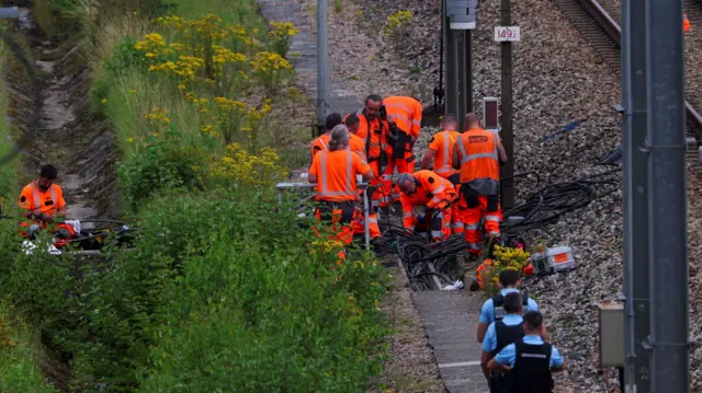 SNCF railway workers and police officers at a site where vandals targeted France's high-speed train network