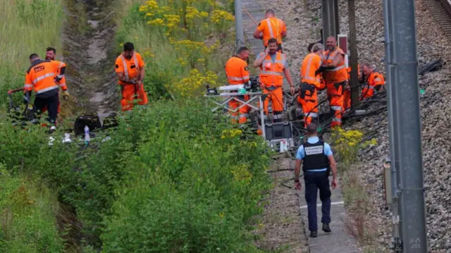 Workers in orange high-vis working along the railway to repair damage