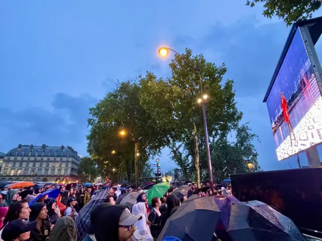 Spectators watch the ceremony in the rain