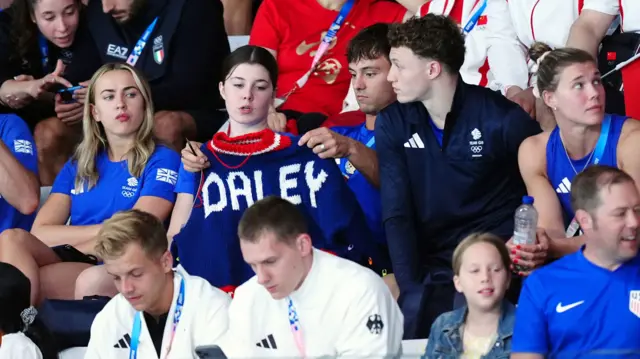 Tom Daley knitting a jumper while watching the diving