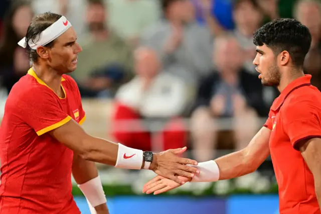 Spain's Carlos Alcaraz (R) and Spain's Rafael Nadal (L) react while they play against Argentina's Maximo Gonzalez and Argentina's Andres Molteni during their men's doubles first round tennis match on Court Philippe-Chatrier at the Roland-Garros Stadium at the Paris 2024 Olympic Games, in Paris on July 27, 2024