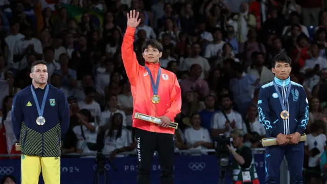 Gold medallist Hifumi Abe of Japan celebrates on the podium with silver medallist Willian Lima of Brazil and bronze medallist Gusman Kyrgyzbayev of Kazakhstan