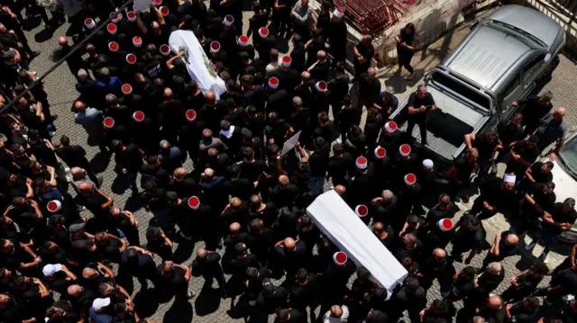 Mourners carry coffins, during the funeral of children who were killed at a soccer pitch by a rocket strike