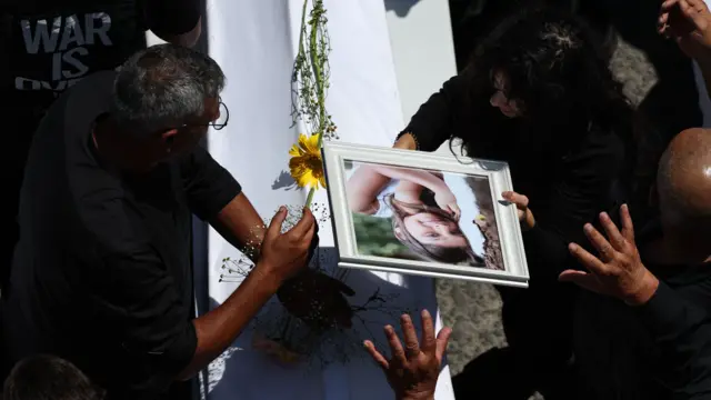 People hold a picture over the coffin of one girl killed in the attack