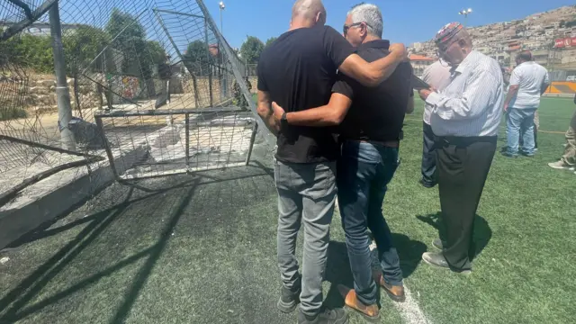 People hug at the scene of the rocket strike in the town of Majdal Shams