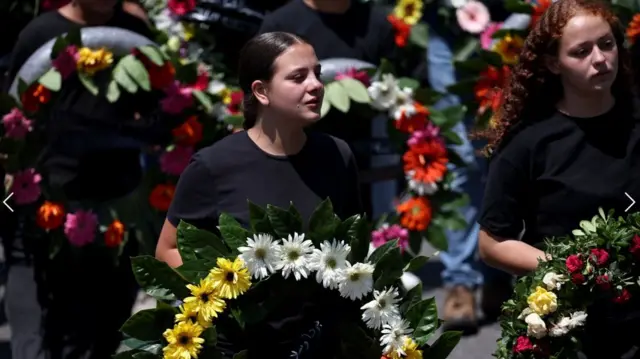 Women carry wreaths for those killed in the strike