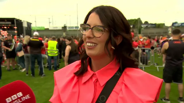 Brown haired girl with glasses in a pink shirt