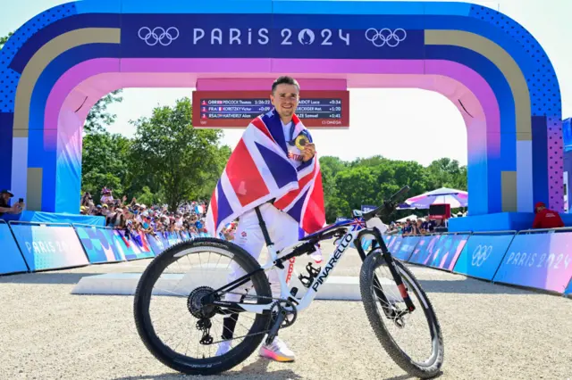 Tom Pidcock poses with his gold medal and bike