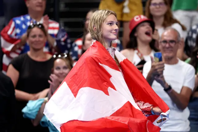 Summer McIntosh walks poolside with the Canada flag