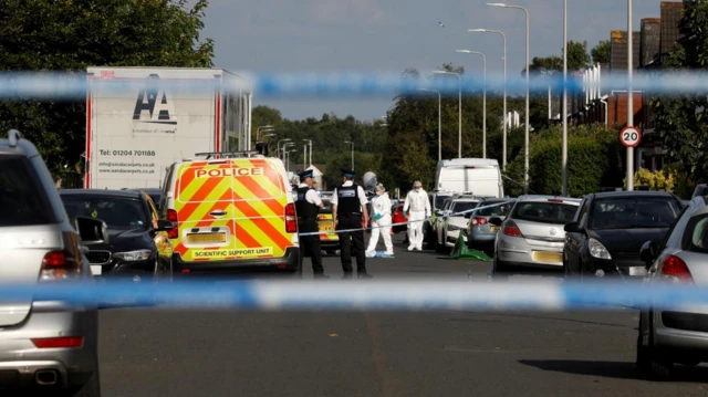 Police officers, including scene of crime officers in covering gear, at the scene behind a cordon on Hart Street