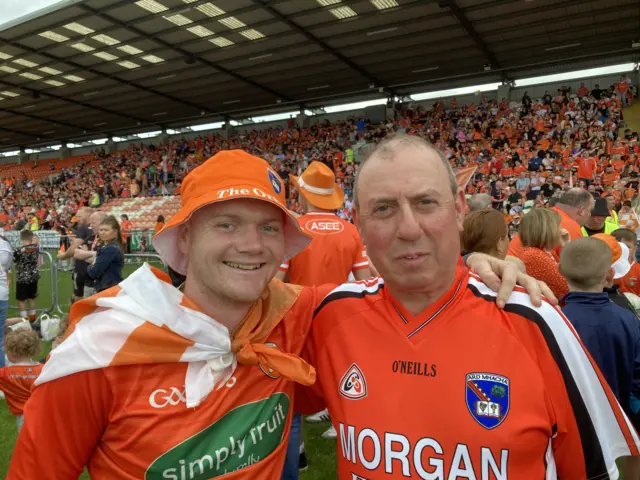 Two men in orange tops at a stadium